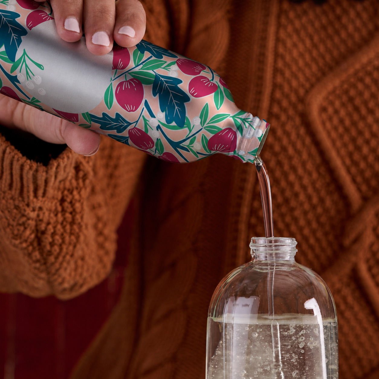 gel dish soap refill being poured into a clear glass dispenser