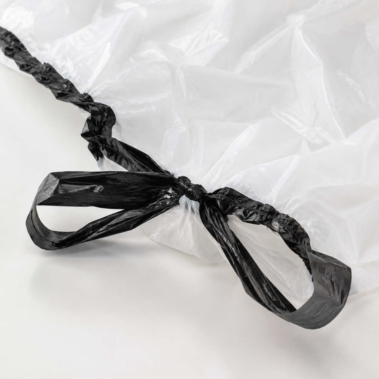 close-up of black drawstring and white recycled plastic trash bag texture