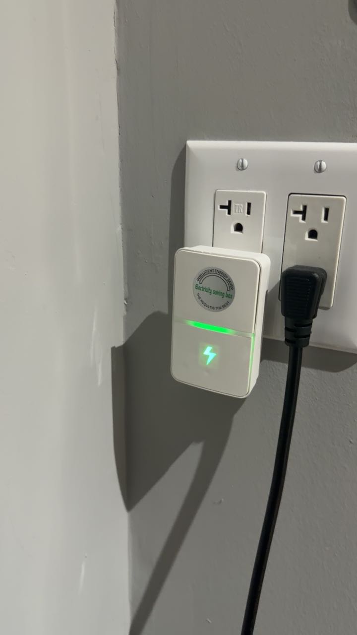 Energy saver plug installed in a wall socket with the LED lit