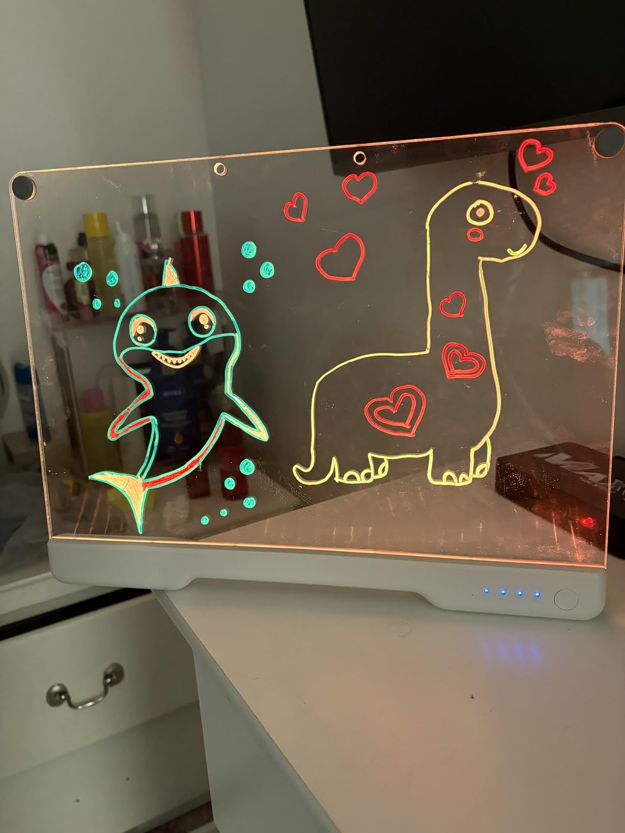 Shark and dinosaur drawings glowing on the LED drawing board