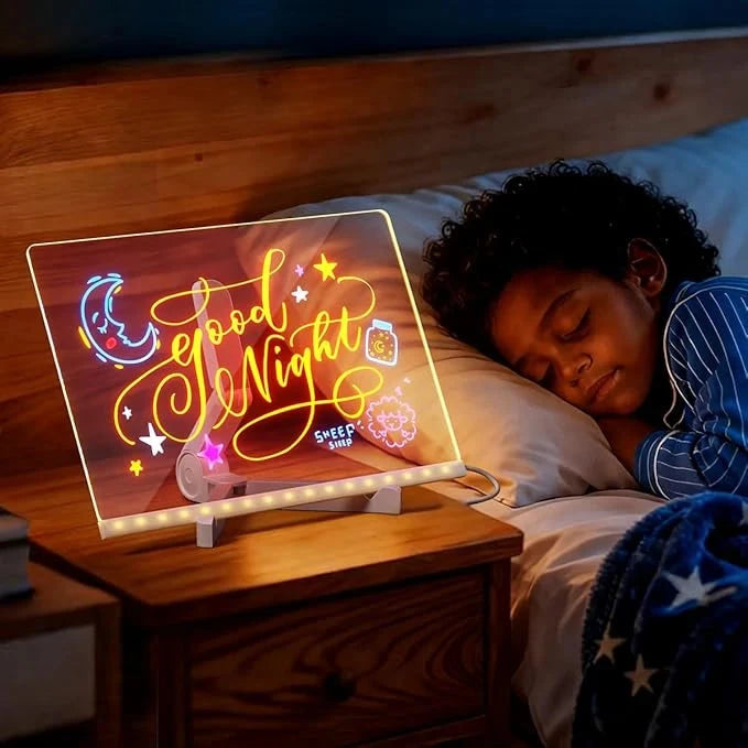 Child asleep beside a glowing good night message on the LED drawing board