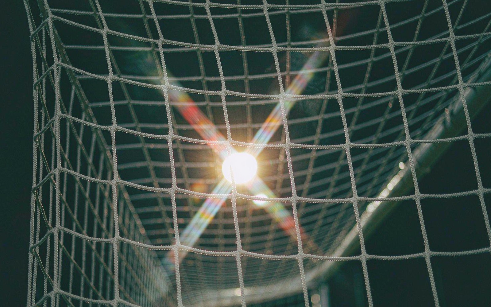 Goal net at night with a floodlight shining through it