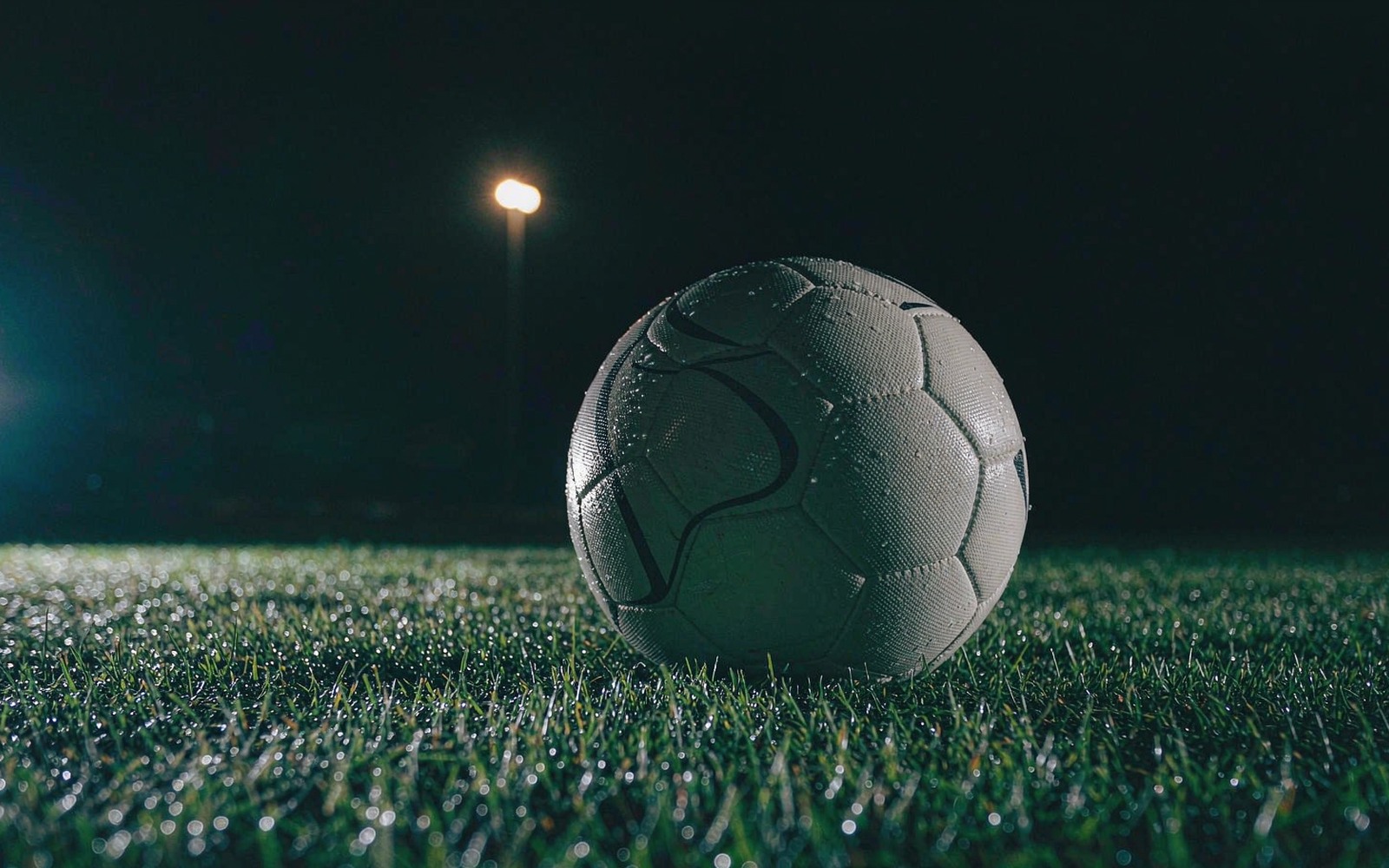 Football resting on dewy grass at night