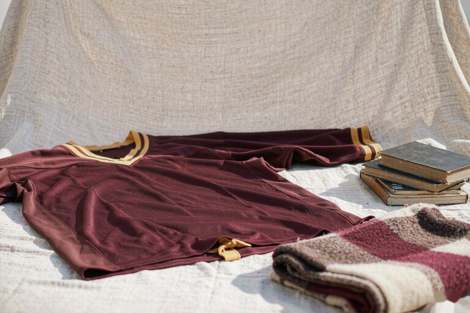 A maroon college jersey with books and a knitted blanket