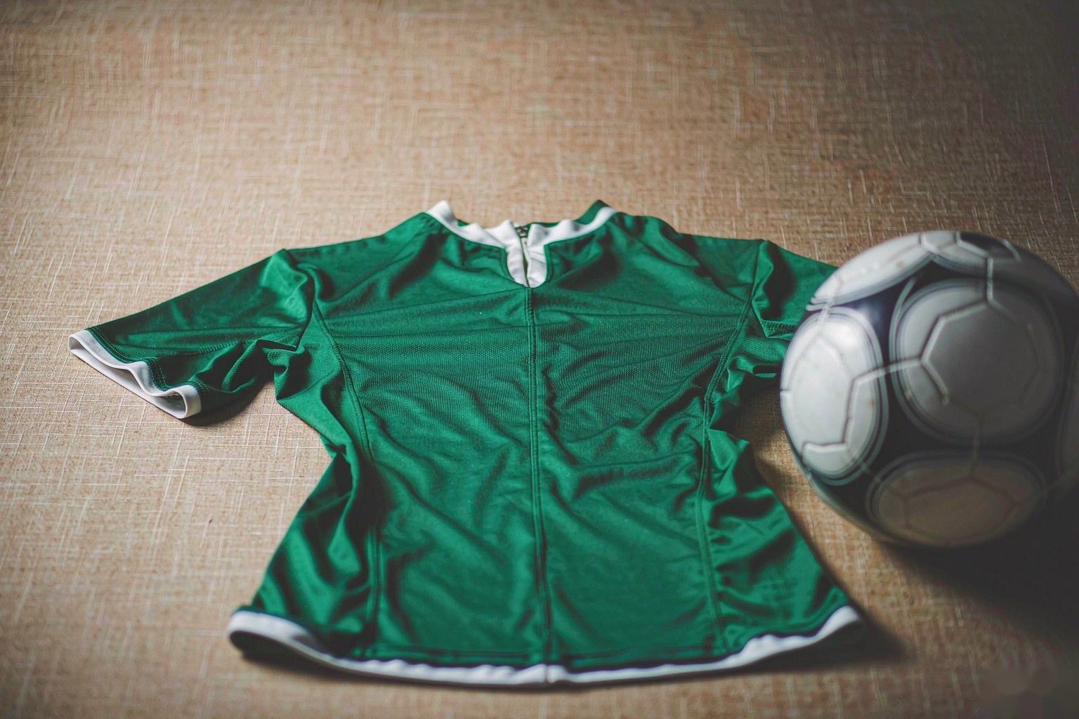 A green soccer shirt with a football on linen