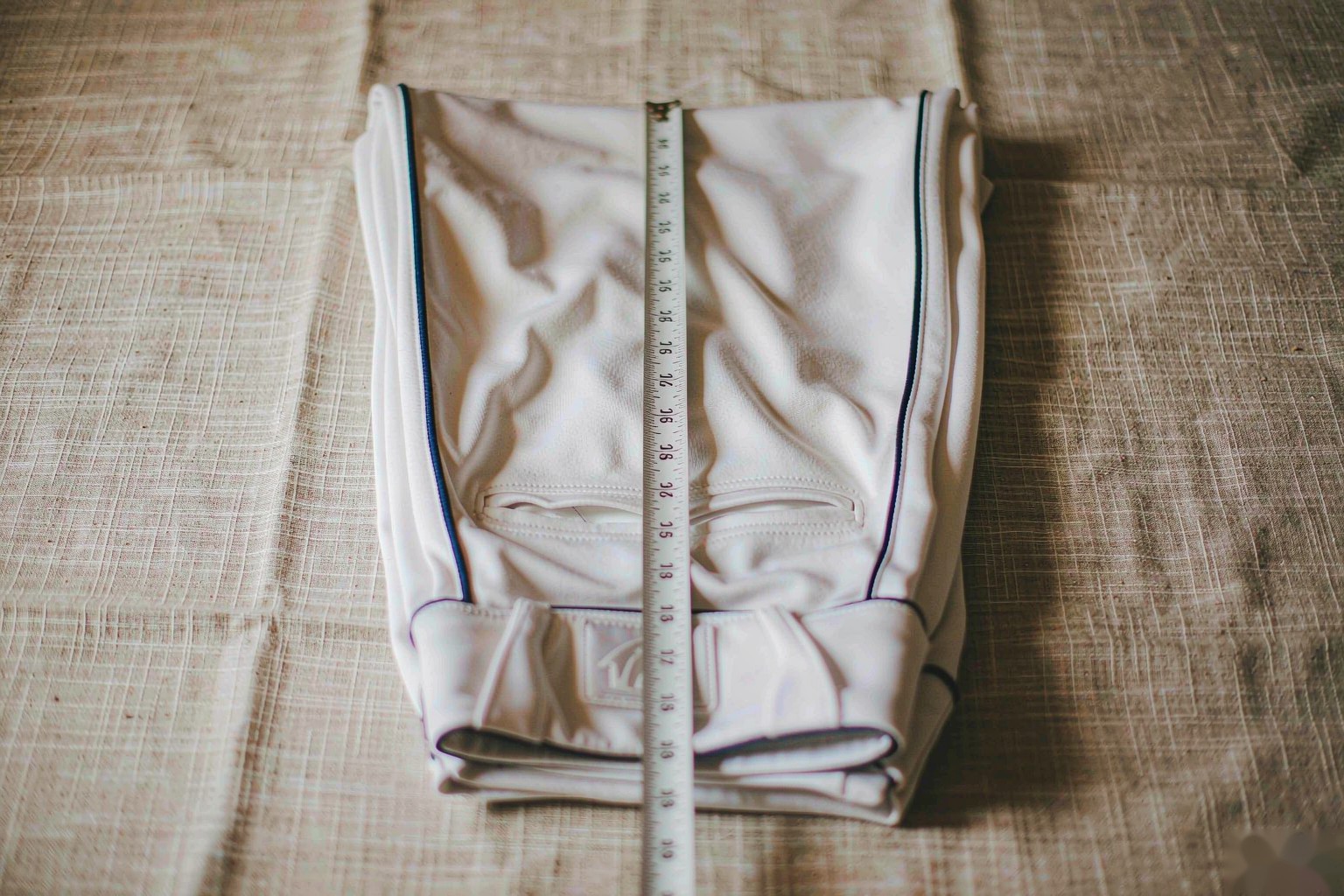 A measuring tape along the inside leg seam of folded baseball pants