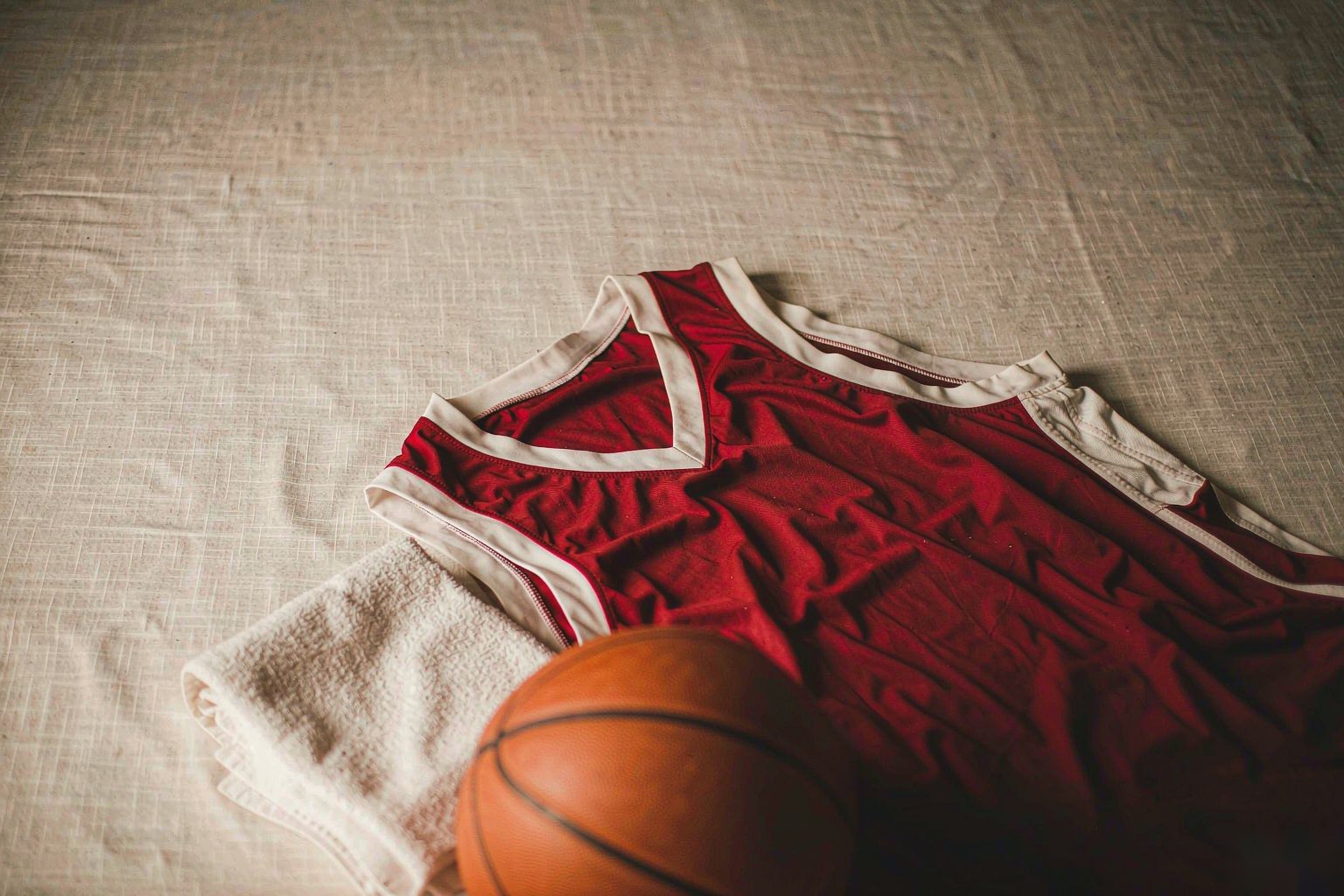 A crimson basketball jersey with an orange basketball on linen