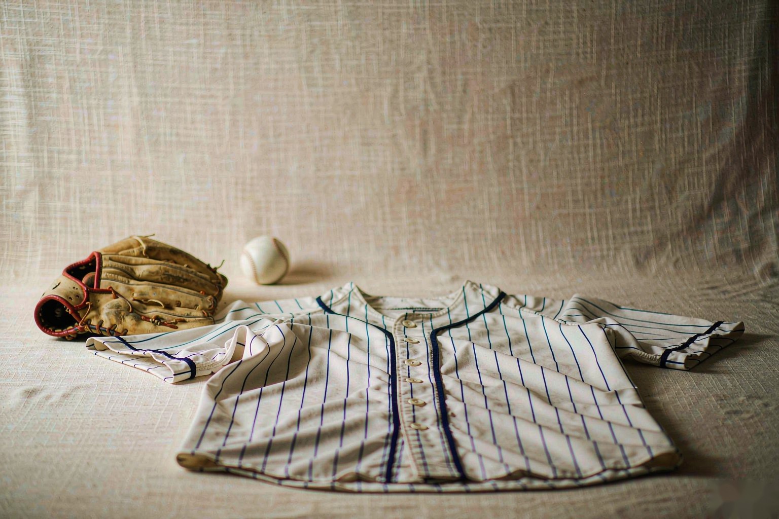 A pinstriped baseball jersey with a leather glove and a ball