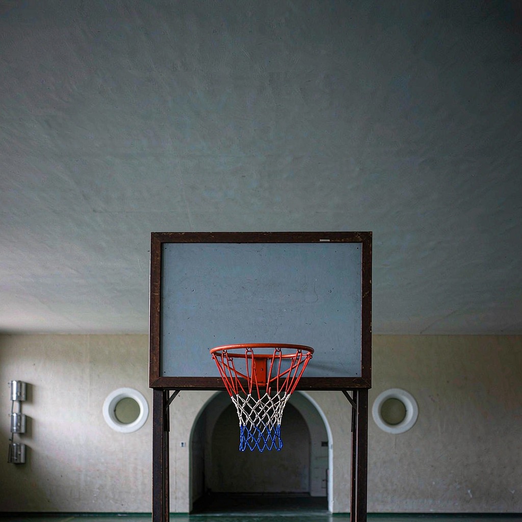 Basketball hoop and backboard from behind in an empty gym