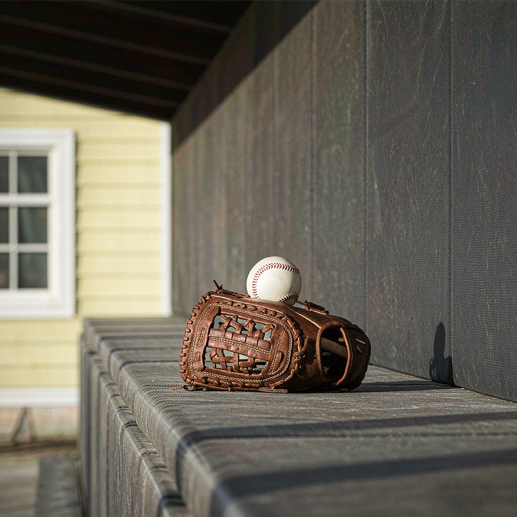 Baseball glove and ball resting on dugout bench