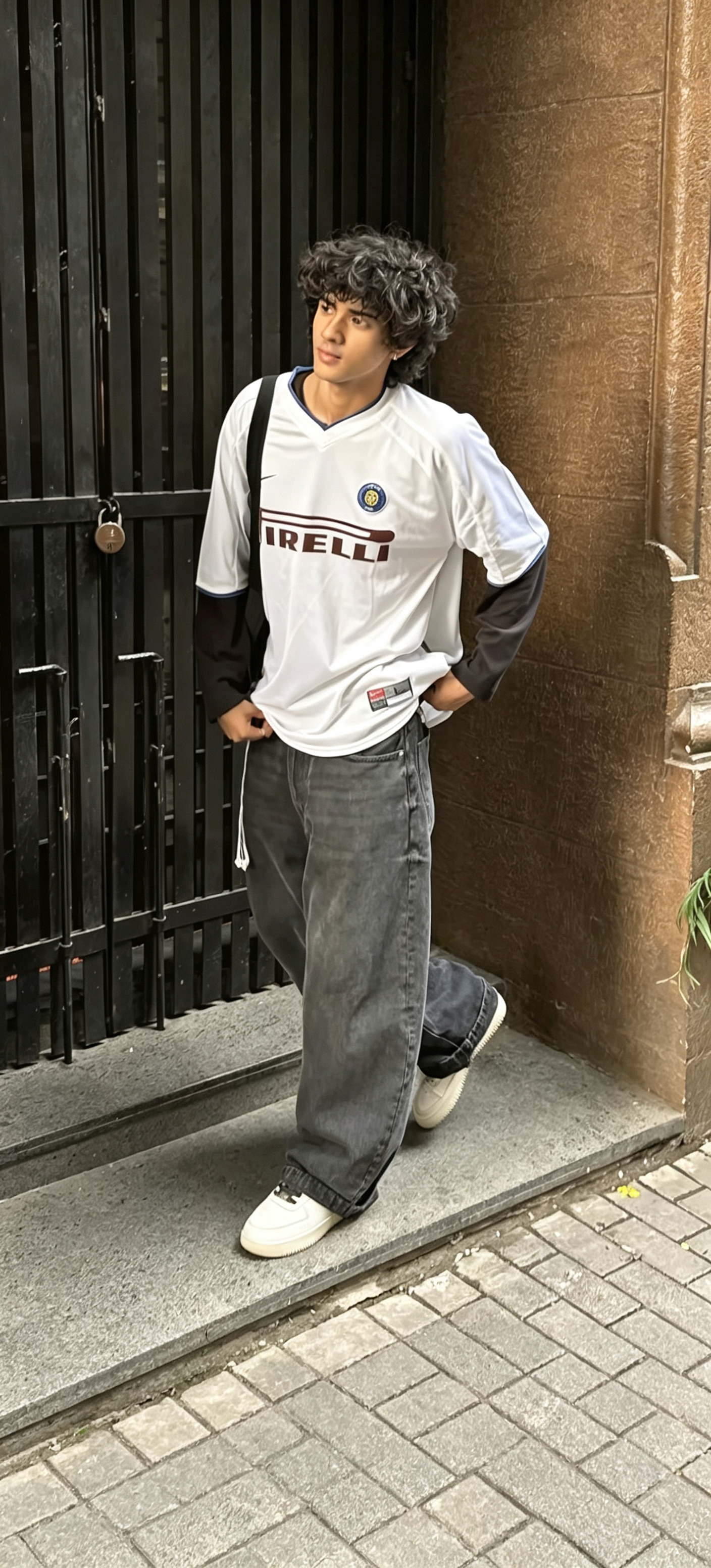 Young man street style wearing vintage Inter Milan long-sleeve football jersey layered over black tee, baggy grey denim jeans, urban streetwear, JerseyHub Pro retro soccer shirt