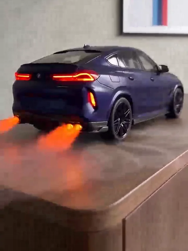 Blue SUV on a wooden cabinet with black wheels, red tail lights and two orange-lit mist streams