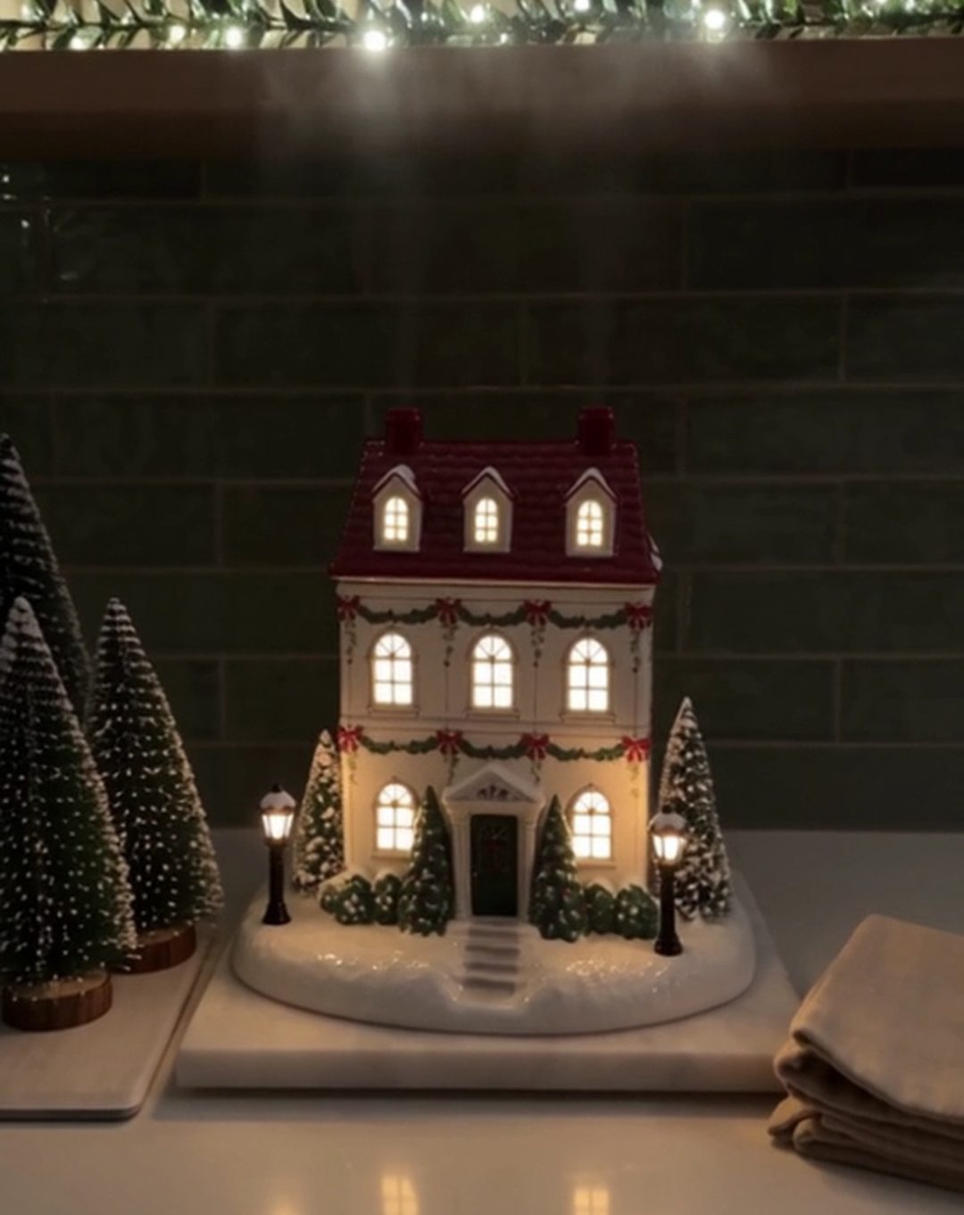 A Christmas cottage diffuser glowing on a kitchen counter