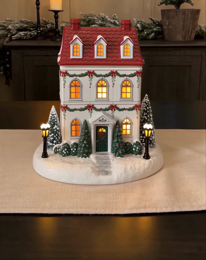 Hand-painted ceramic cottage with festive greenery and window lights