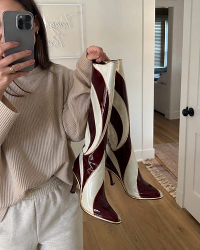 Candy Cane boots held in front of a mirror