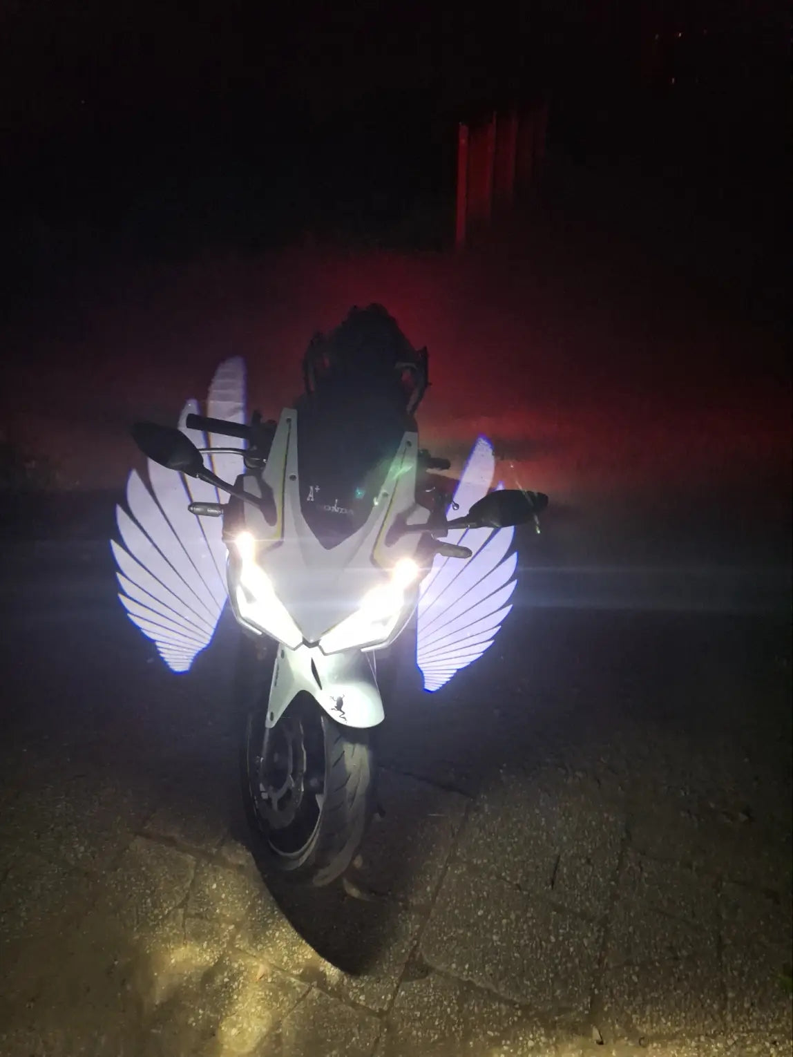 White wings projected beside a motorcycle after dark