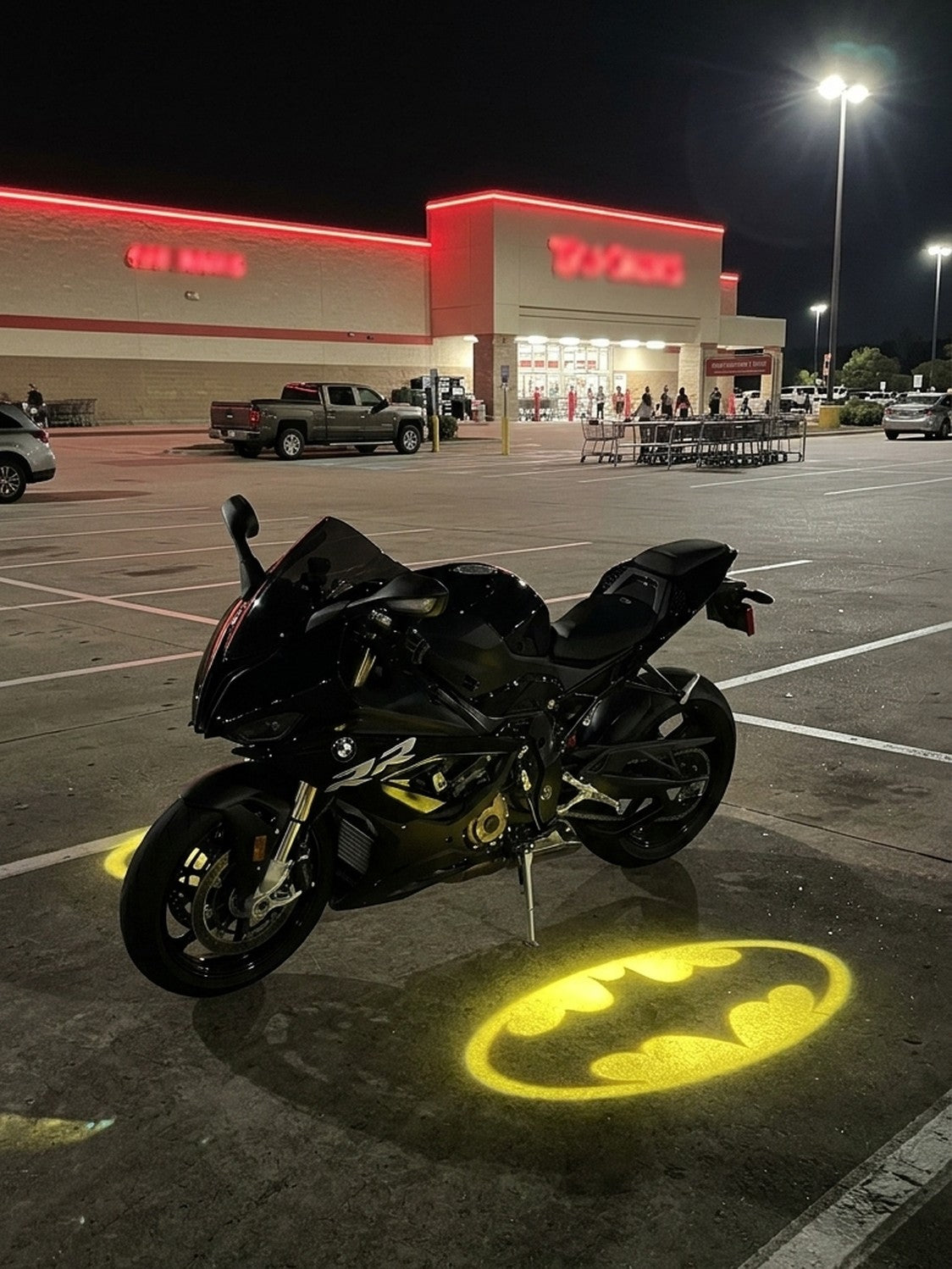 Golden bat projection beside a parked motorcycle