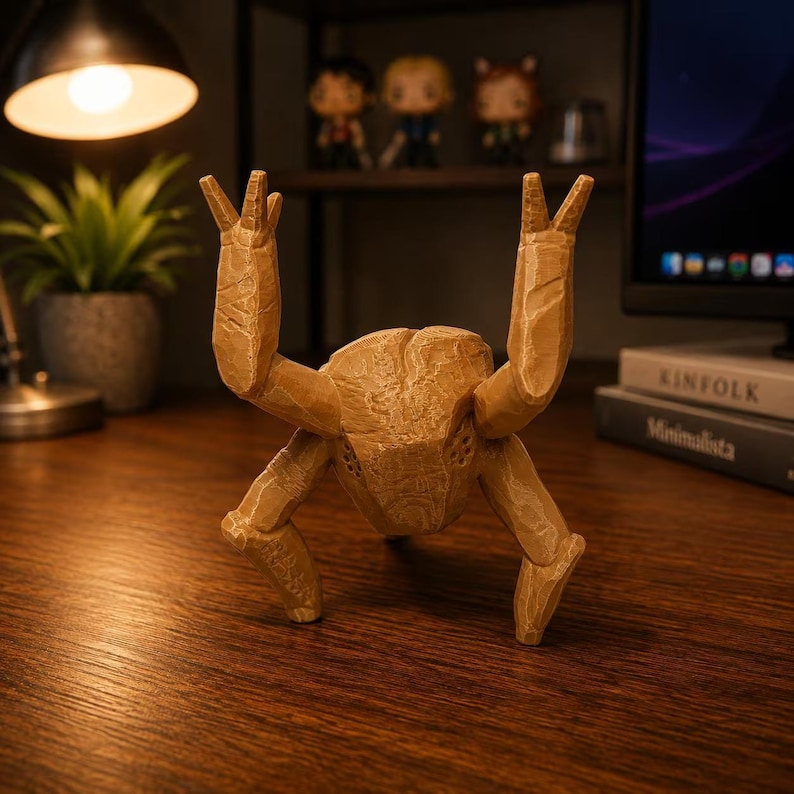 May include: A tan, multi-legged creature figurine with a textured, carved appearance. The object features a central body with two raised upper limbs and two lower limbs positioned for stability, showcasing a layered, 3D-printed aesthetic.