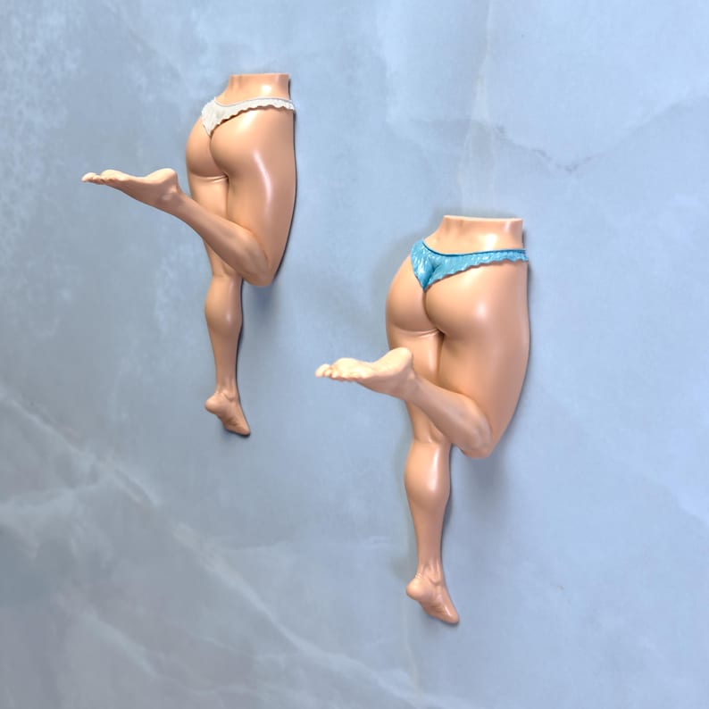 May include: Two decorative figurines of legs, one with white lace trim underwear and the other with blue lace trim underwear. The figurines are posed in a playful, dancing position against a light blue background.