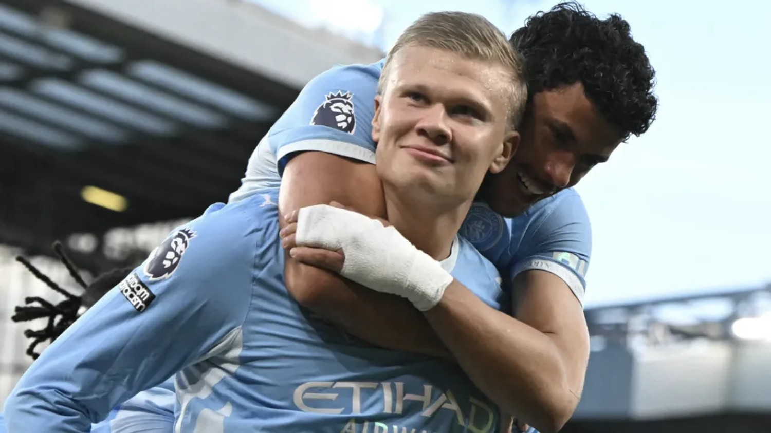 Two Manchester City players embracing in the sky blue home shirt after the win at Anfield