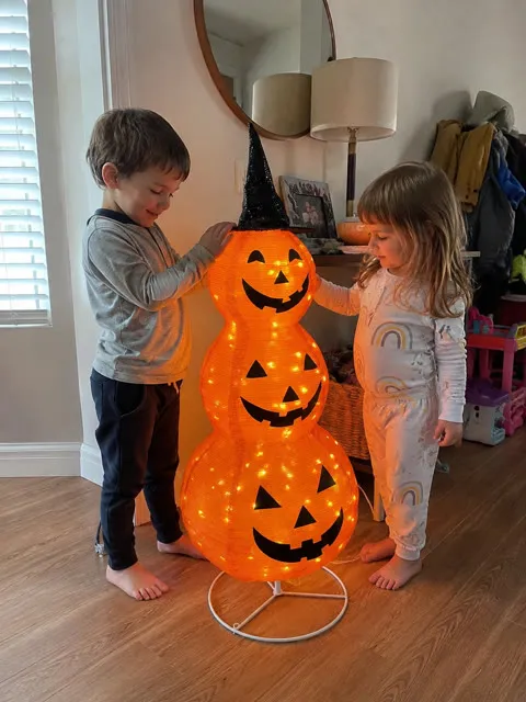 Children admiring the lighted pumpkin lantern indoors