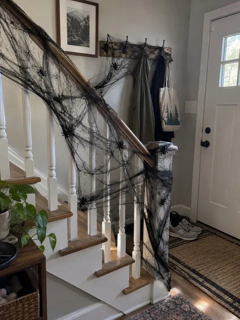Black spider web spread across a home entry stair rail