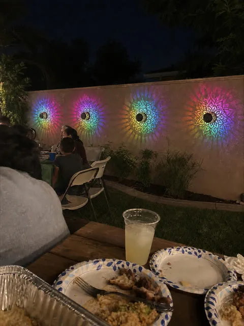 Four colorful mandala wall lights glowing during a backyard cookout