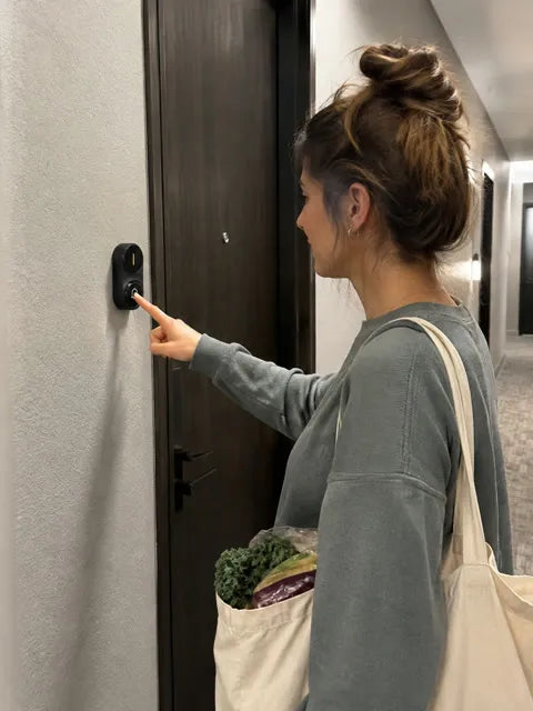 An apartment visitor pressing a black wireless doorbell button