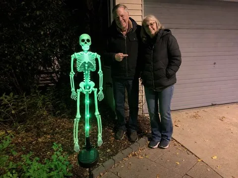 Green solar skeleton yard stake beside a driveway