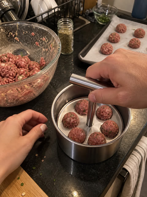Couple preparing a tray of meatballs in a small apartment kitchen