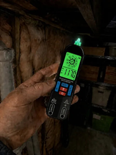 Smart pen multimeter illuminating a cable in a dim basement utility area
