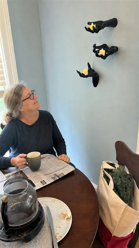 Three black hand candle holders on a blue breakfast nook wall