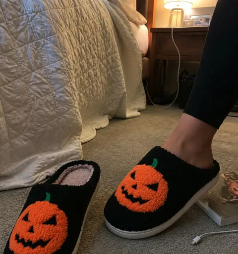 Black pumpkin slippers beside a bedroom quilt