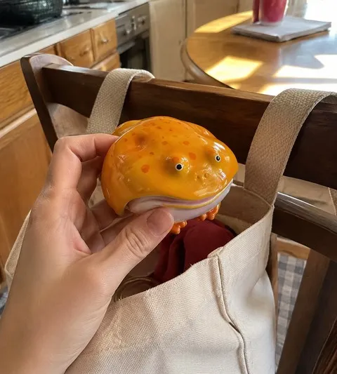 Yellow frog earbud case lifted from a canvas tote