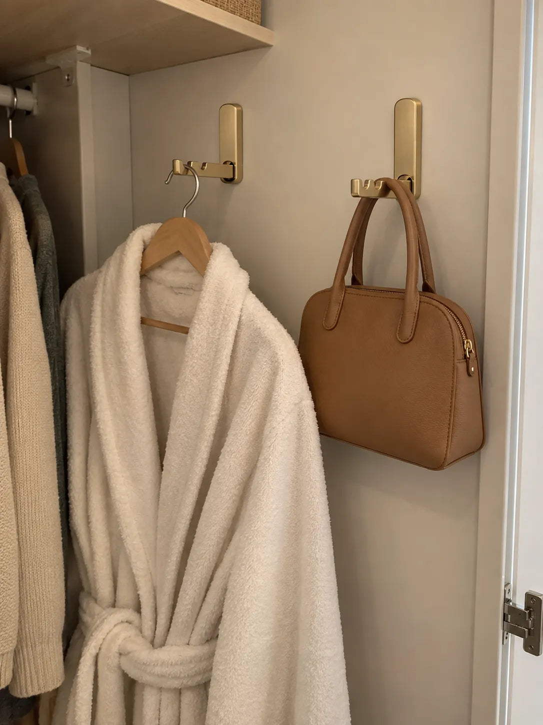 Gold folding hooks holding a robe and handbag in a bedroom