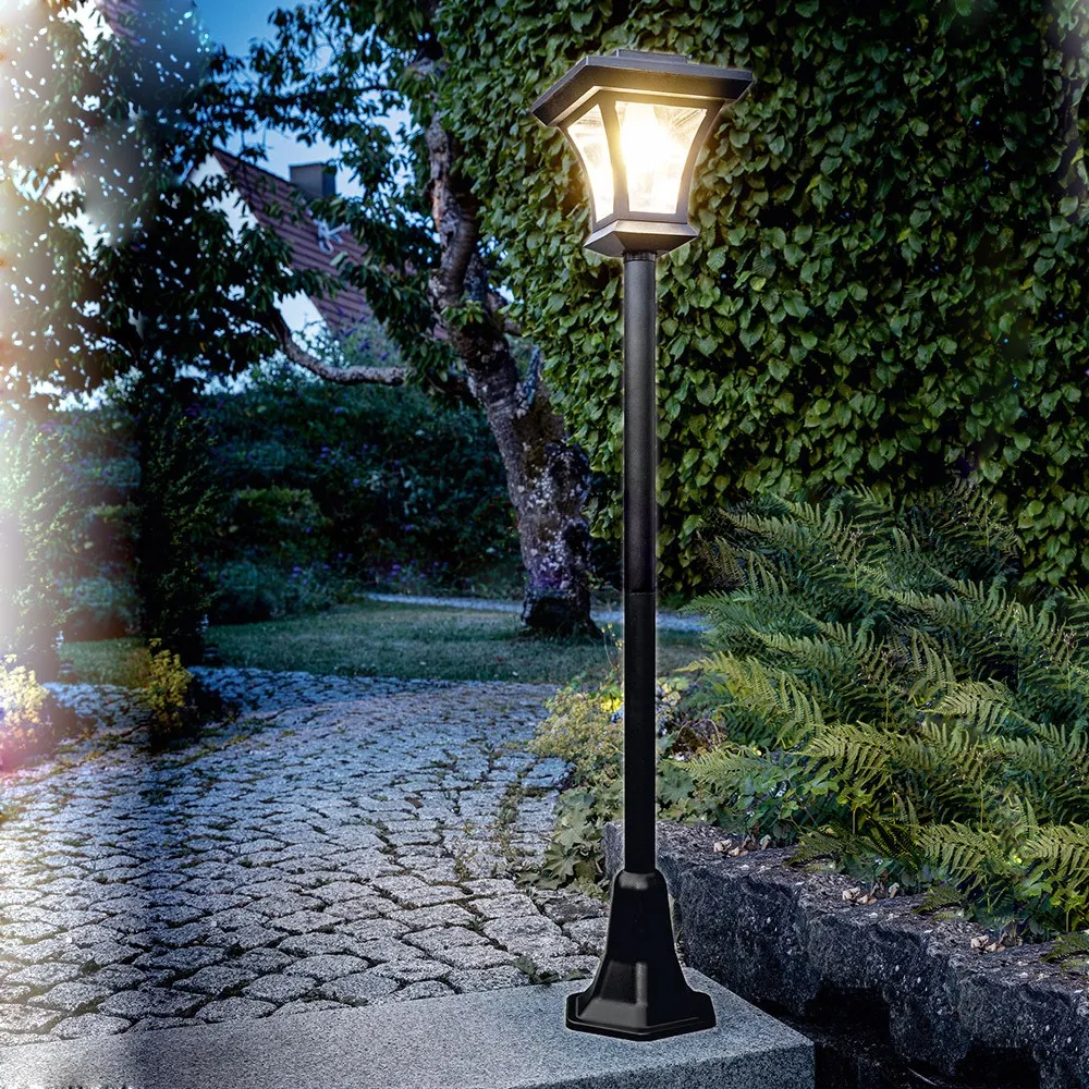 Black solar courtyard lamp beside a garden path