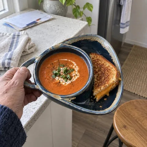 Navy blue divided ceramic bowl holding tomato soup and grilled cheese in a small kitchen