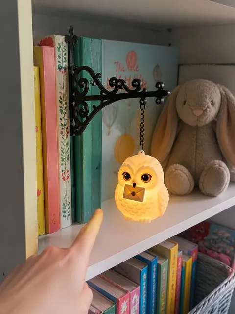 Owl light hanging from a bracket inserted between children's books in a colorful reading nook
