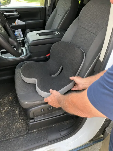 Integrated support cushion being placed on a pickup truck seat