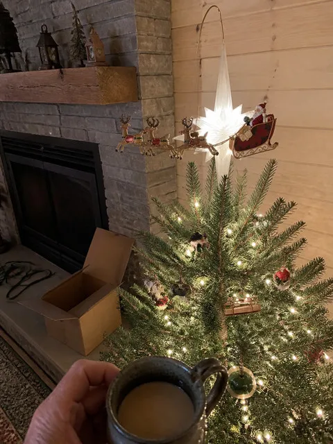 Animated topper on a smaller tree beside a stone fireplace