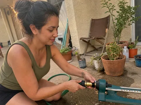 Woman attaching a hose to a patio sprinkler