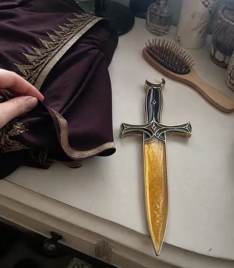 Amber Gold potion dagger beside costume fabric on a vanity