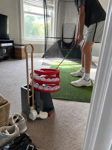 Family practice room with a golf ball dispenser beside the mat