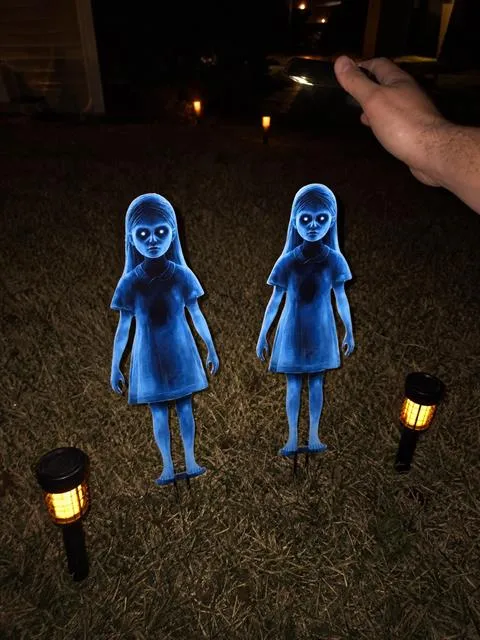 Two blue ghost-girl yard stakes photographed at night with a flashlight