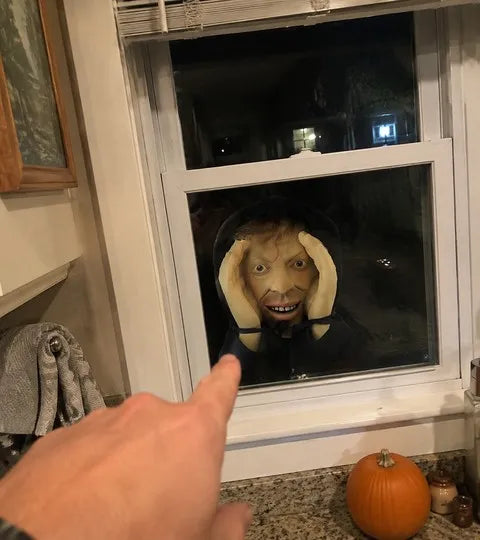 Peeping face prop seen through a kitchen window at night