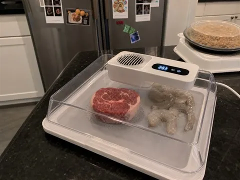 White defrosting box operating unattended with steak and shrimp fully enclosed