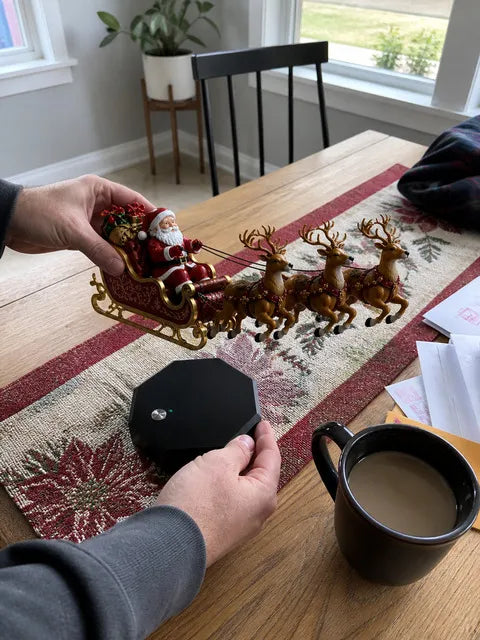 Hands positioning the Santa sleigh above its magnetic base on a dining table