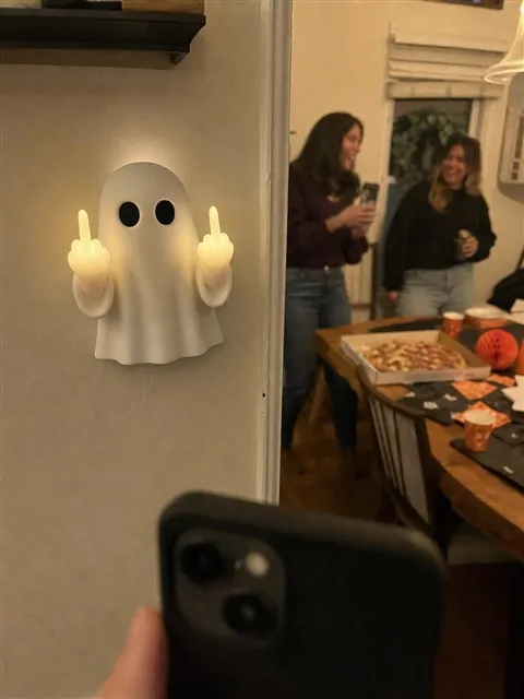 Ghost wall light beside an adults-only Halloween gathering