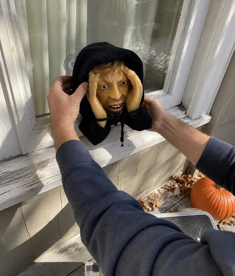 Halloween window peeper prop being attached to clean glass