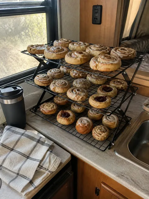 Three-tier cooling rack holding pastries in a compact RV kitchen